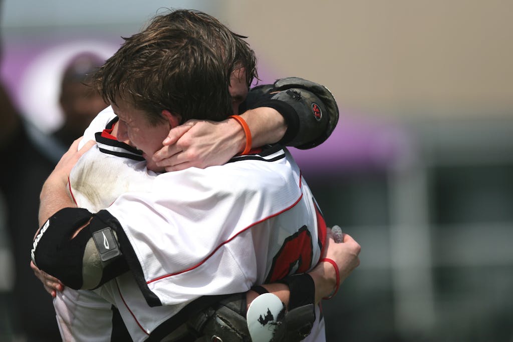 Athletes celebrating a victory with an emotional embrace on the field.